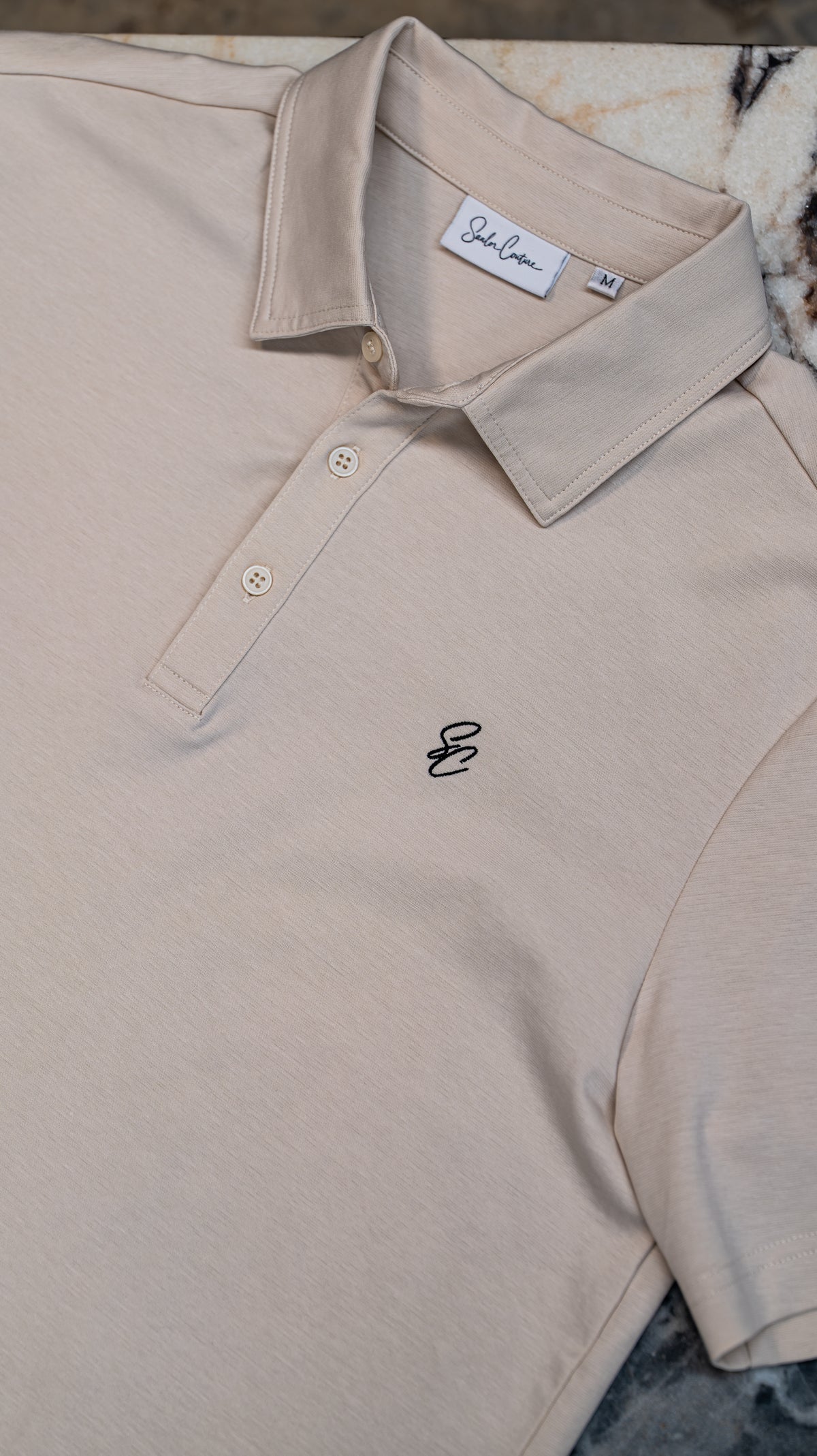 Le Classique Polo in cream, close-up of collar and chest monogram
