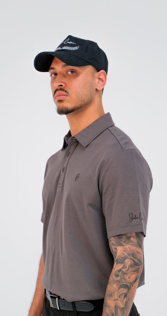 Model wearing Le Classique Polo in charcoal with a Saalor Couture cap