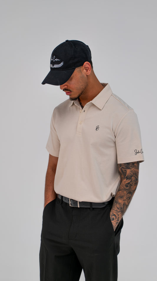 Model wearing Le Classique Polo in cream with black trousers and a Saalor Couture cap