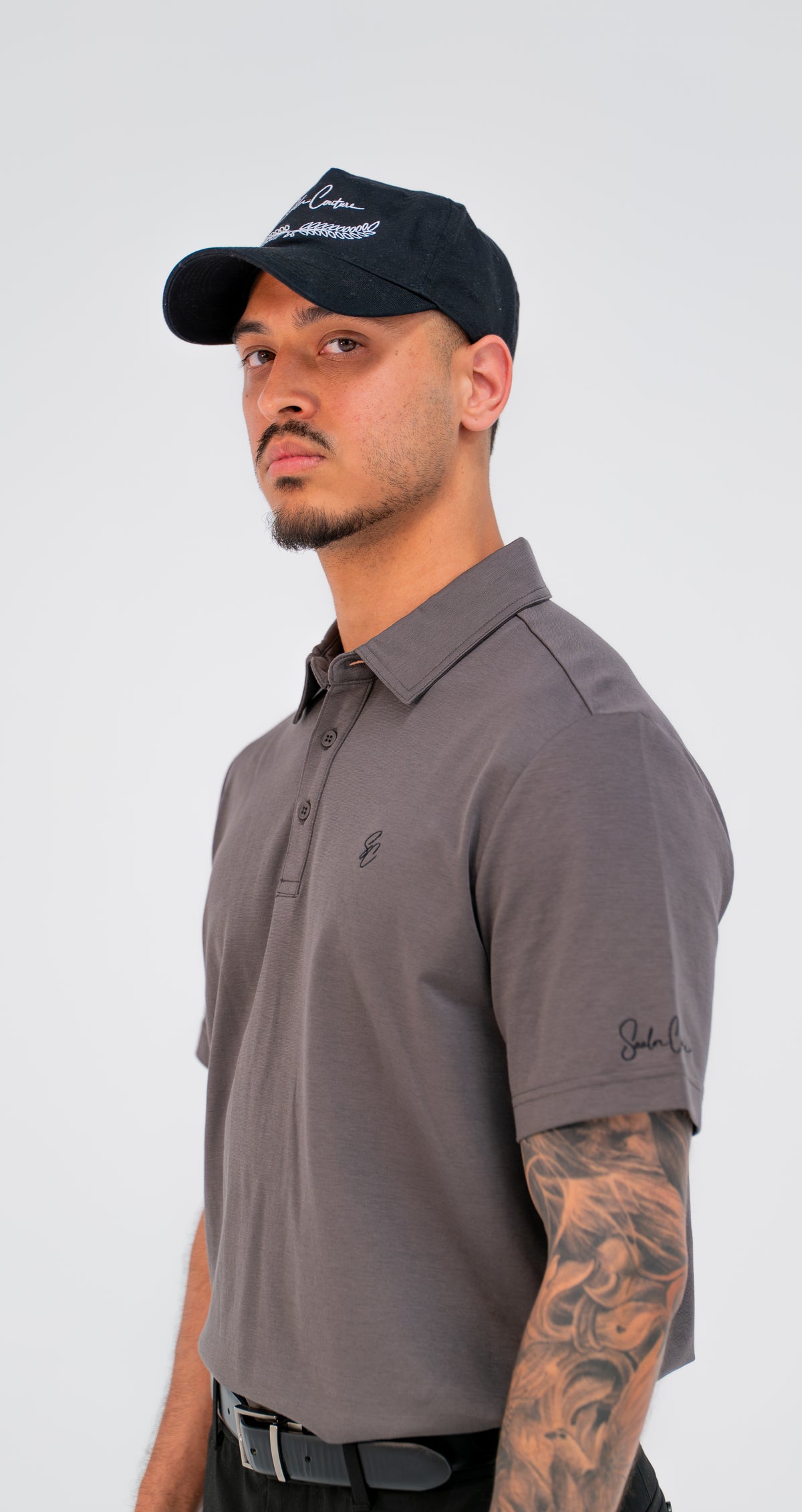 Model wearing Le Classique Polo in charcoal with a Saalor Couture cap