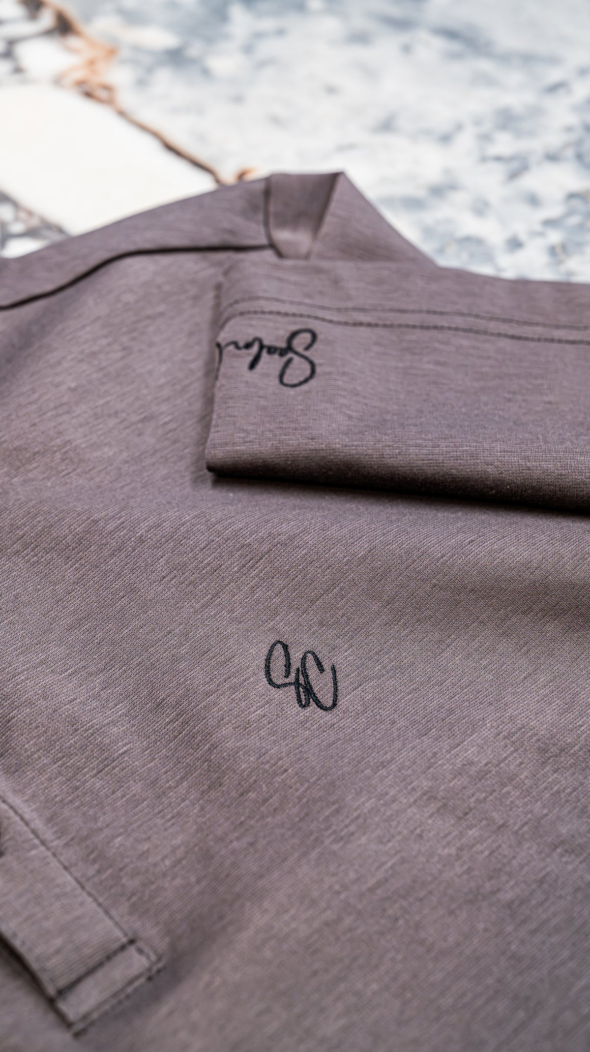 Le Classique Polo in lilac, close-up of embroidered monogram and sleeve signature