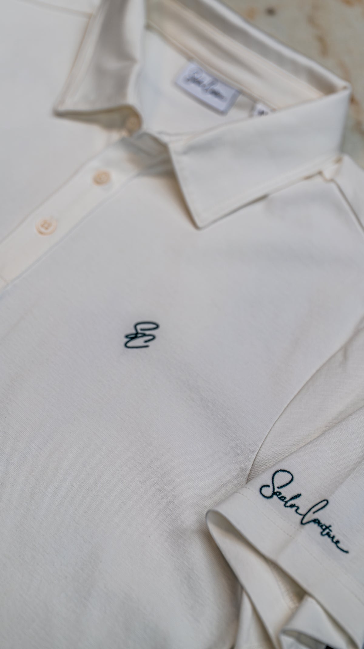 Le Classique Polo in white, close-up of embroidered monogram and sleeve signature