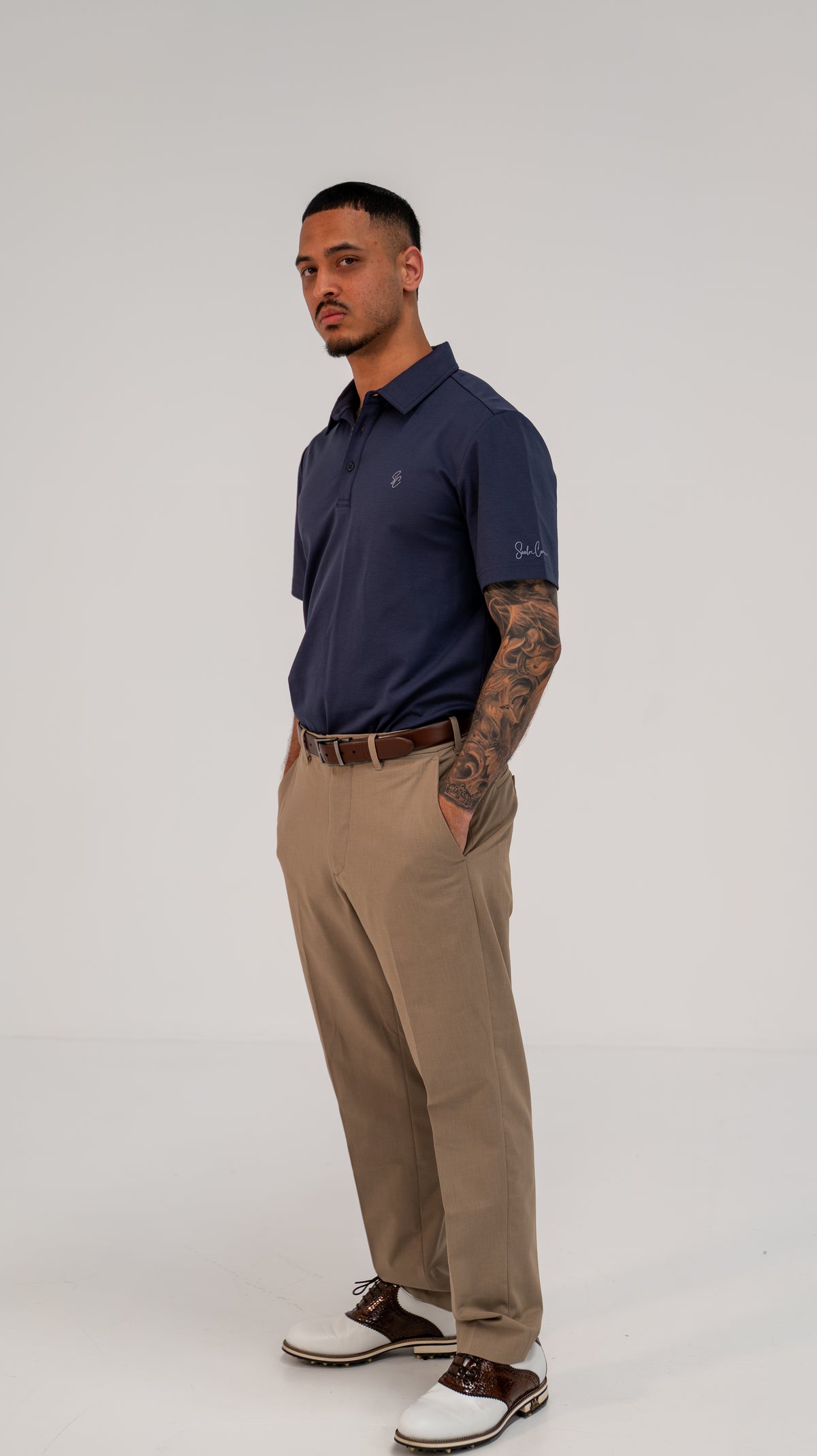 Model wearing Le Classique Polo in navy with tan trousers, full-length view