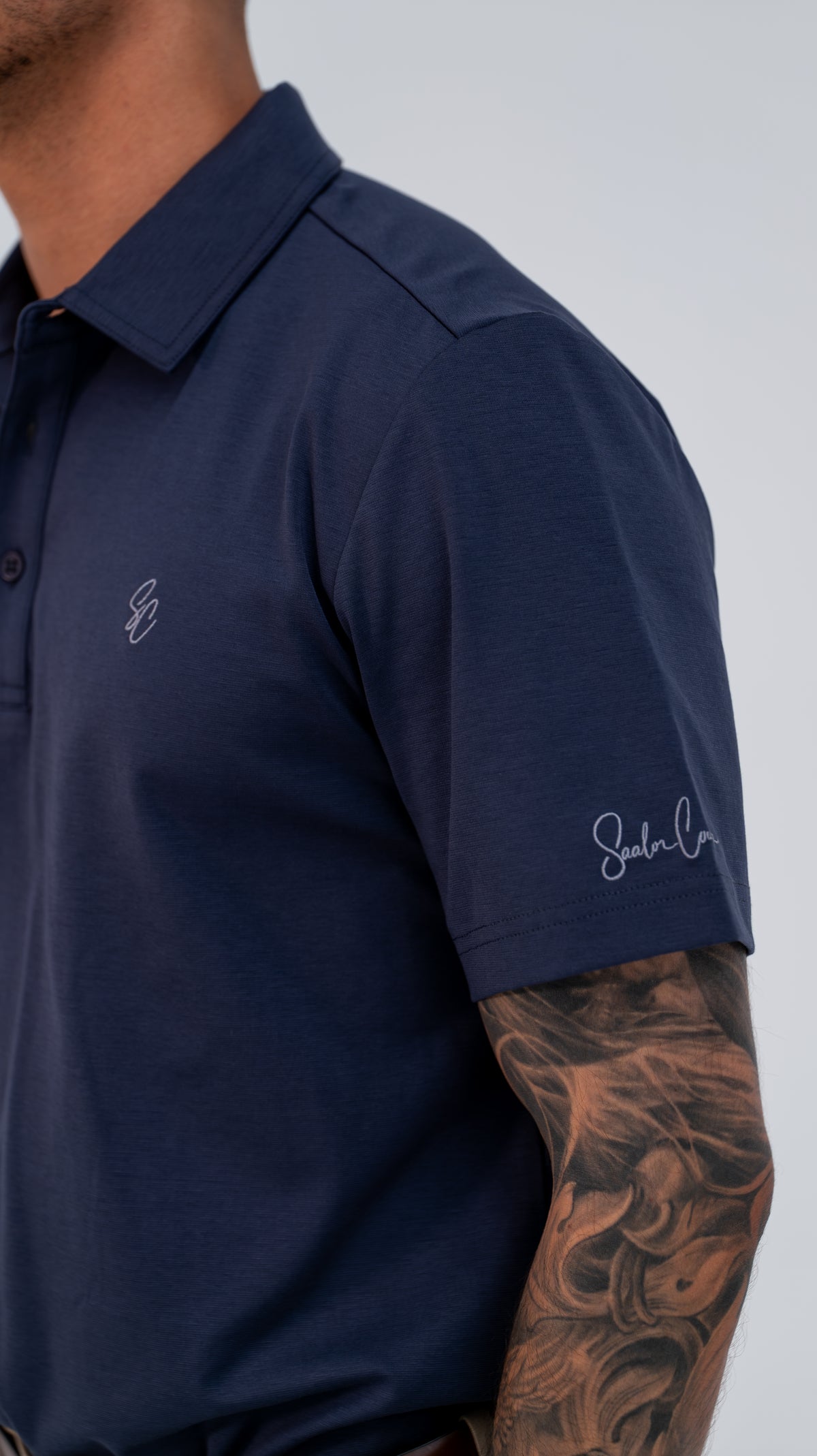 Le Classique Polo in navy, close-up of chest monogram and sleeve signature