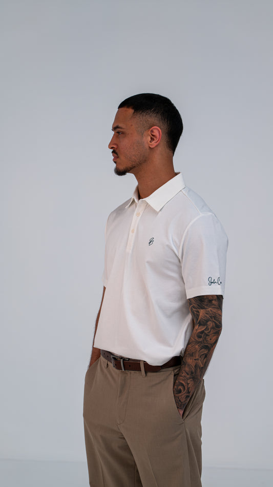 Model wearing Le Classique Polo in white with tan trousers, side view